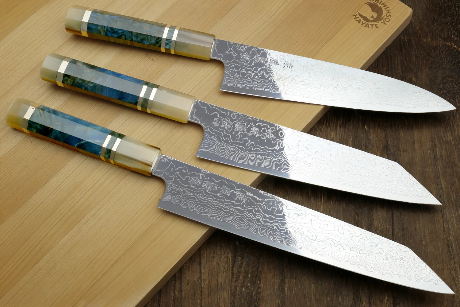 Three damascus knives resting gently on a cutting board