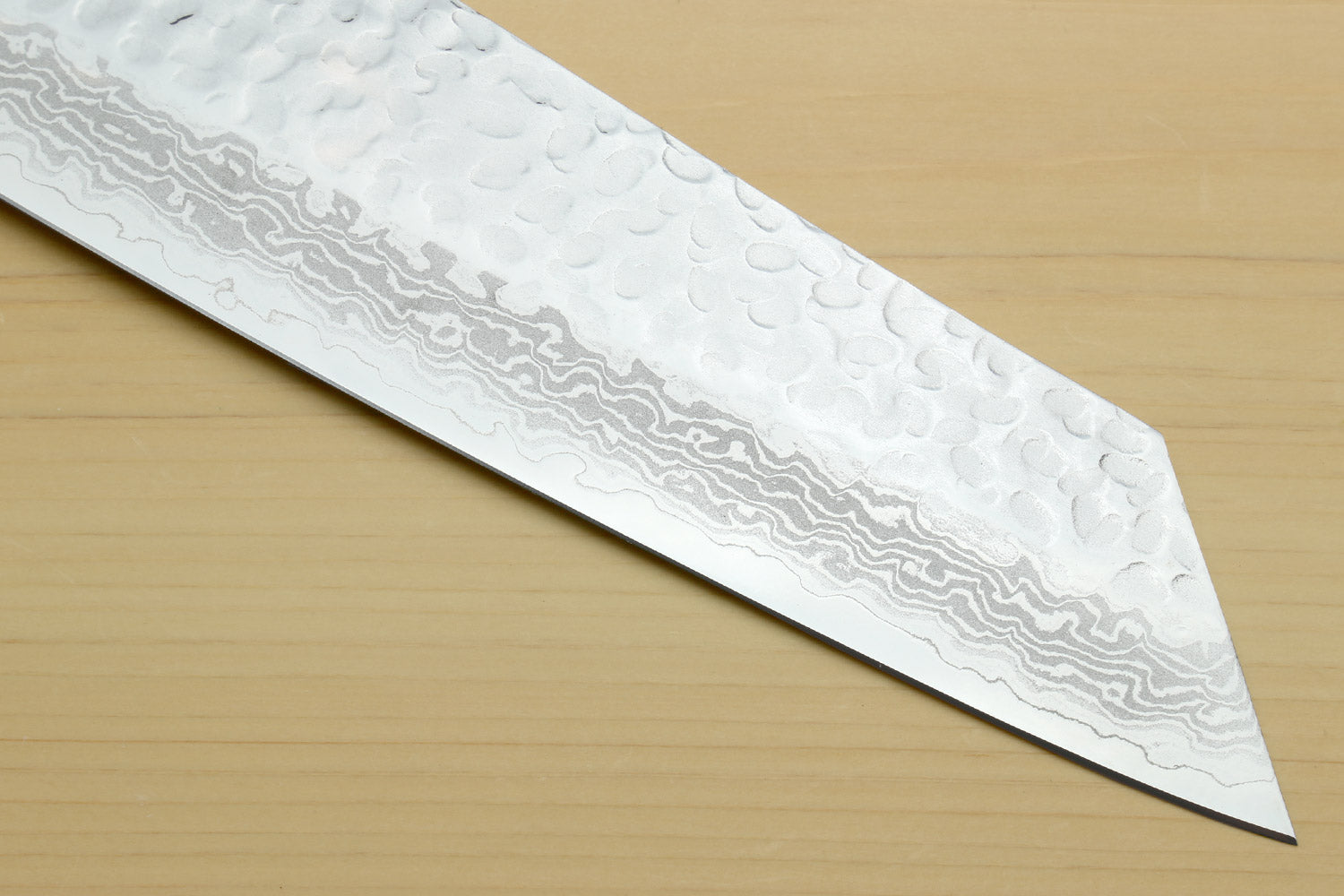 Kiritsuke chef knife blade close-up with hammered Damascus pattern along the edge