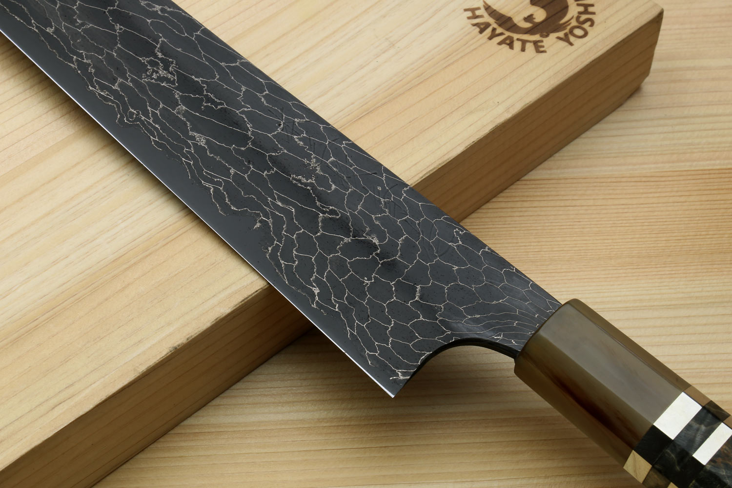Sujihiki slicer knife with black snake-skin Damascus blade and dark handle on stand