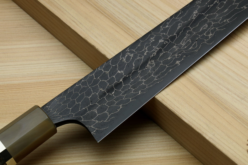 Sujihiki slicer knife blade close-up with dark snake-skin Damascus pattern