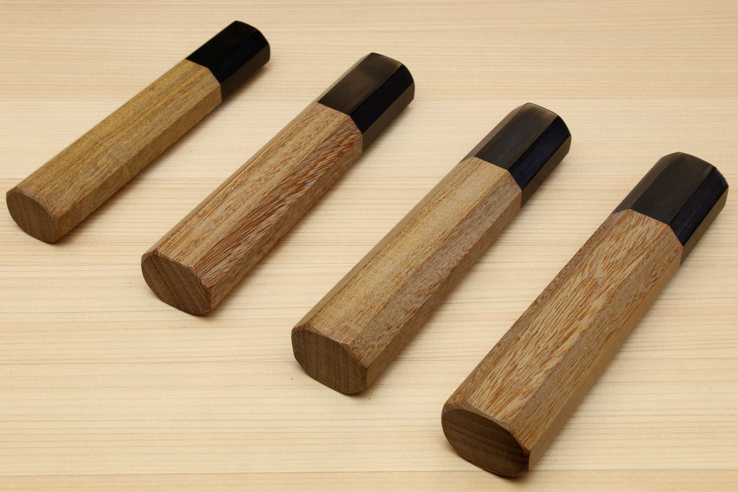 Gyuto chef knife handles with ebony bolsters and ambrosia wood grips, angled shots
