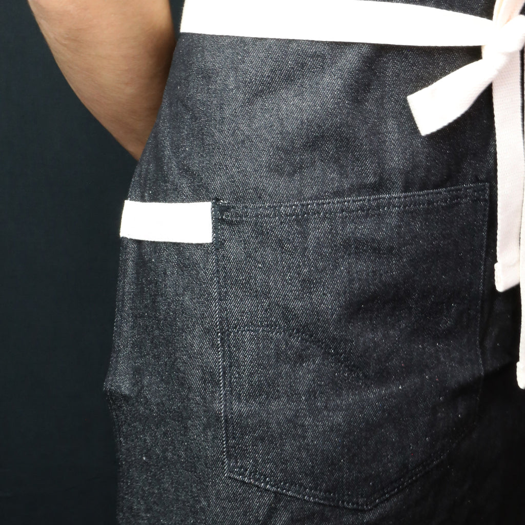 Dark denim kitchen apron with chest pocket and white stitched trim