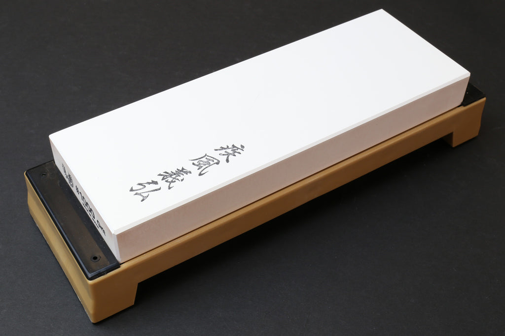 White whetstone on wooden base with black abrasive strip at one end