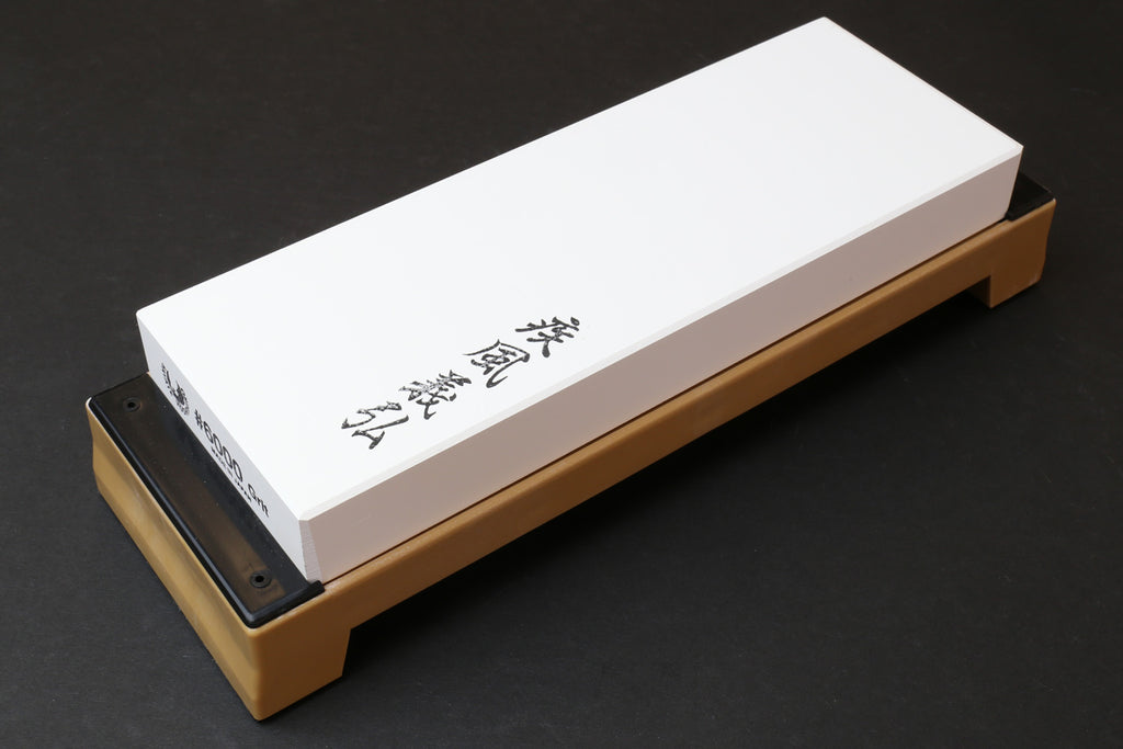6000 grit sharpening whetstone on tan base, white stone angled view