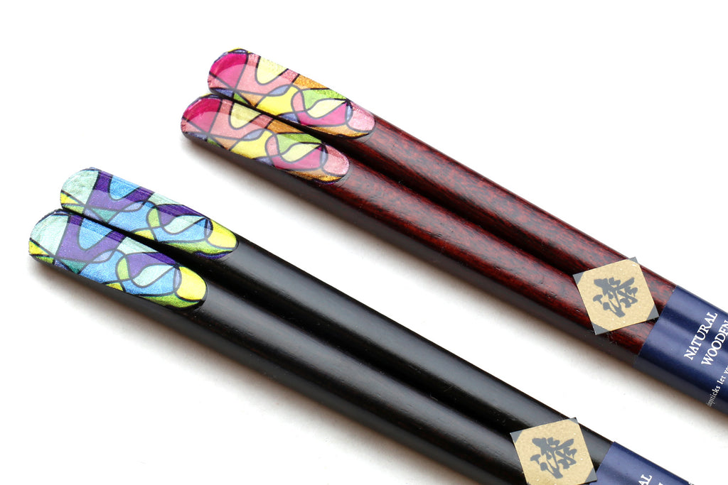 Pair of lacquered chopsticks with colorful retro graphic ends and dark bodies.