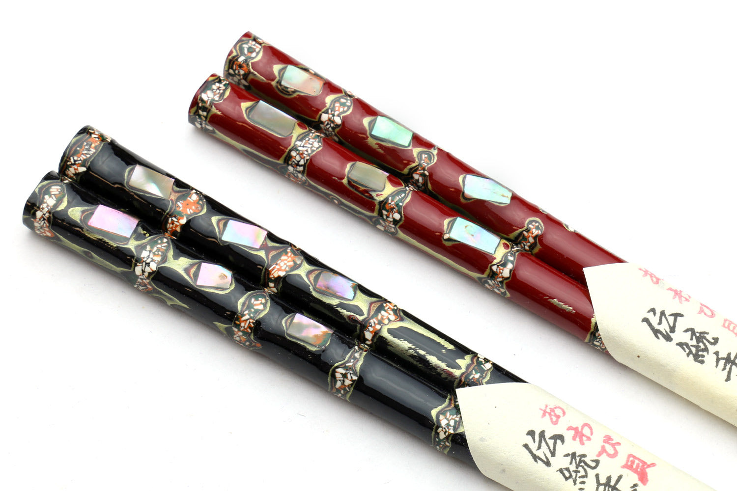 Two pairs chopsticks: red and black, glossy with ornate cap details
