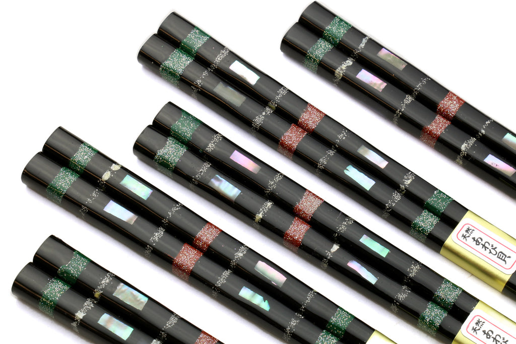 Five black chopsticks with green and red mosaic bands along the center