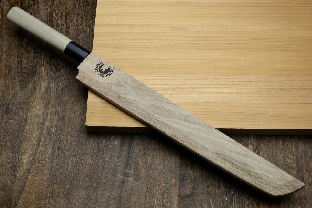 Wooden saya cover with carved emblem, partially fitted over a blade