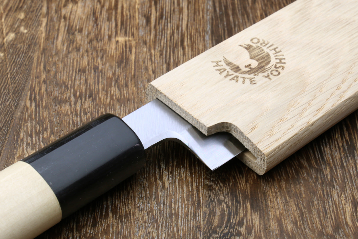 Wooden saya cover with cutout channel and black handle peeking, light oak