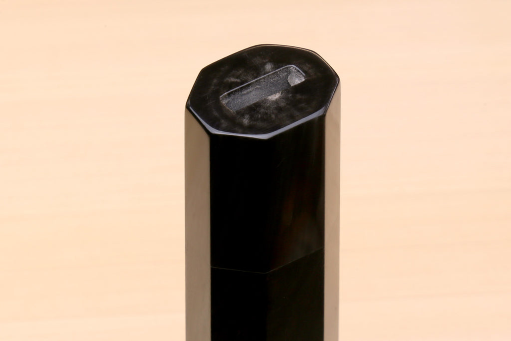 Horn bolster end on an ebony knife handle, faceted cut