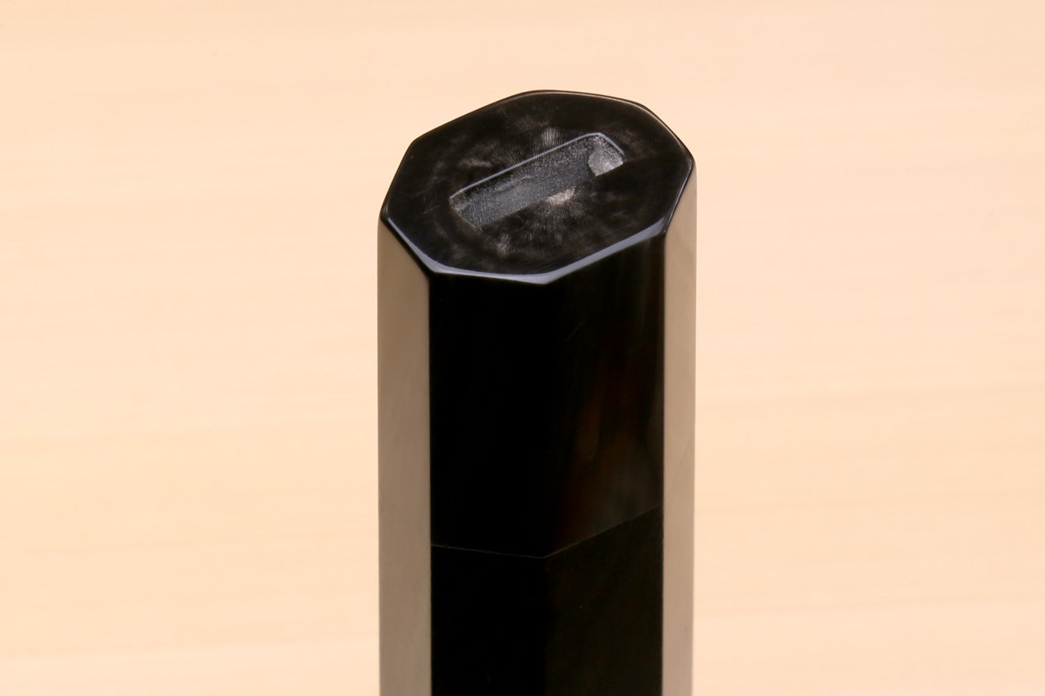 Horn bolster end on an ebony knife handle, faceted cut
