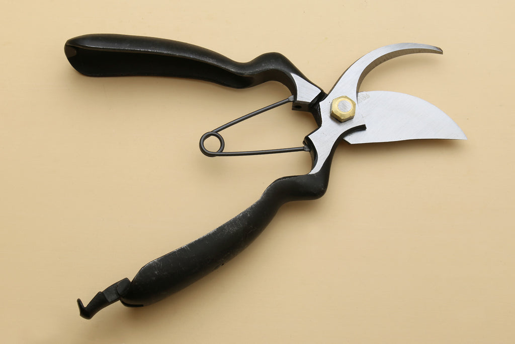 Pruning shears with white curved blade and black textured grip handles