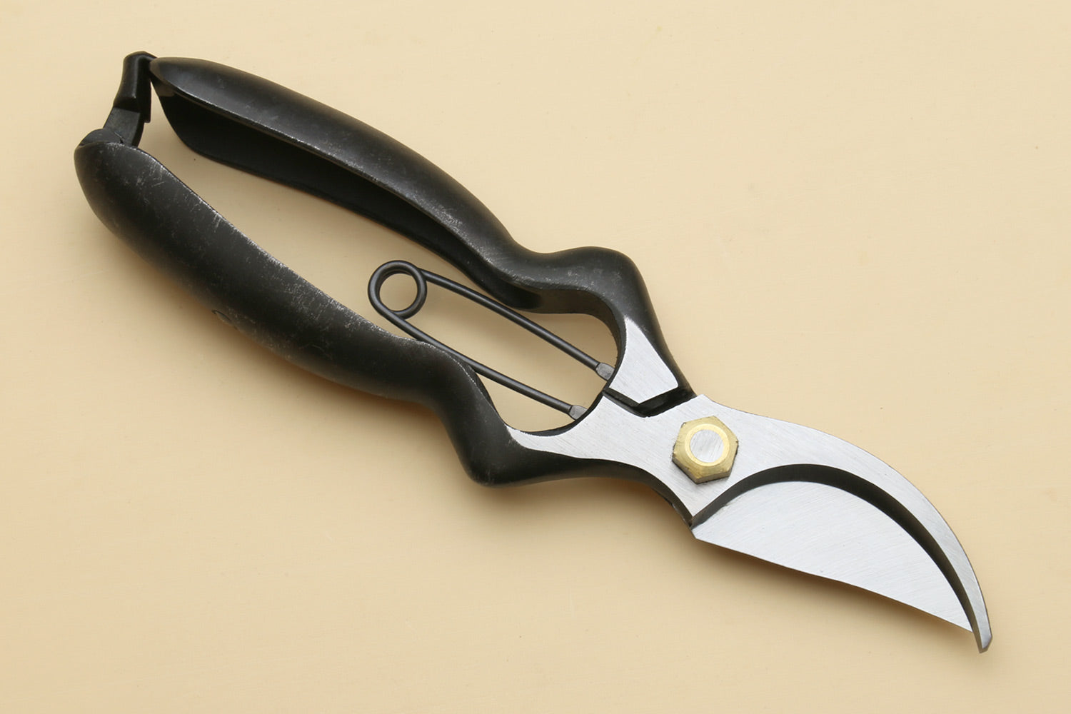 Black pruning shears with white curved blade and finger-loop handle, angled view
