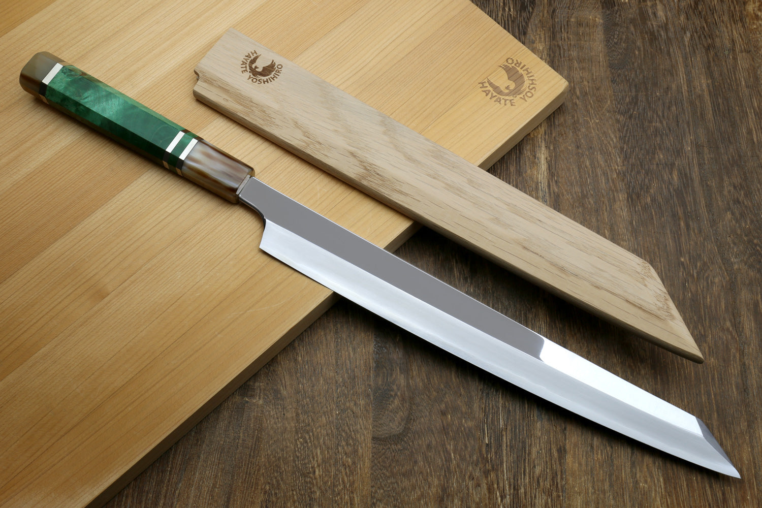 Japanese sushi knife with mirror-finished stainless blade and green-accent handle on board