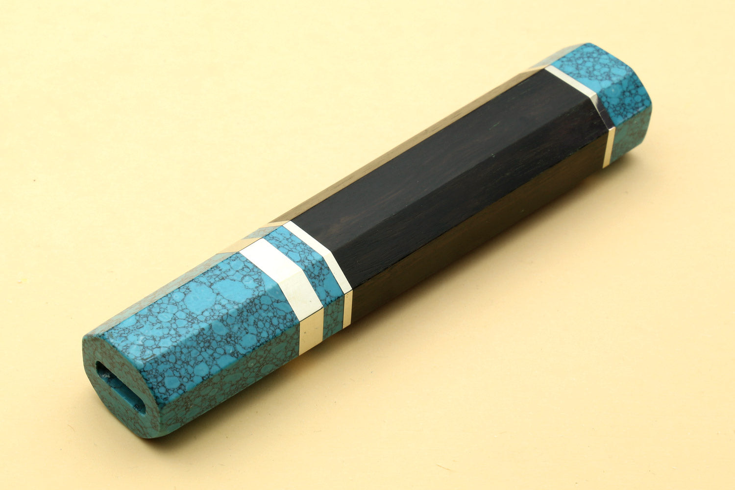 Turquoise-blue knife handle with black core and white stripe, angled view