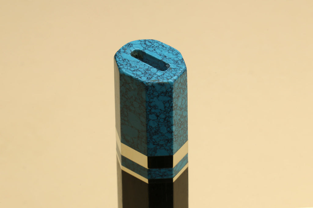 Turquoise-blue knife handle with black core and white stripe near the end