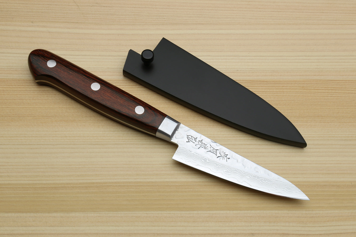 Paring knife with dark brown wood handle and hammered Damascus blade with black sheath