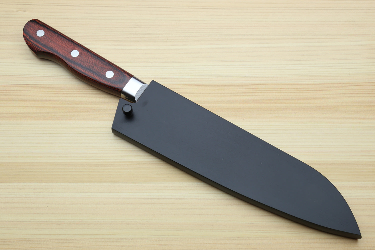 Santoku chef knife with black sheath (saya) on light wood surface