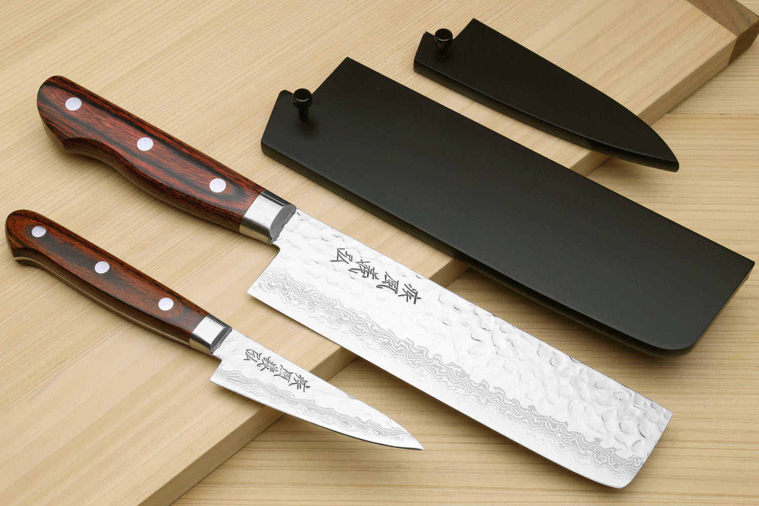 Damascus stainless steel knife set with hammered blades, dark wood handles, black blade covers