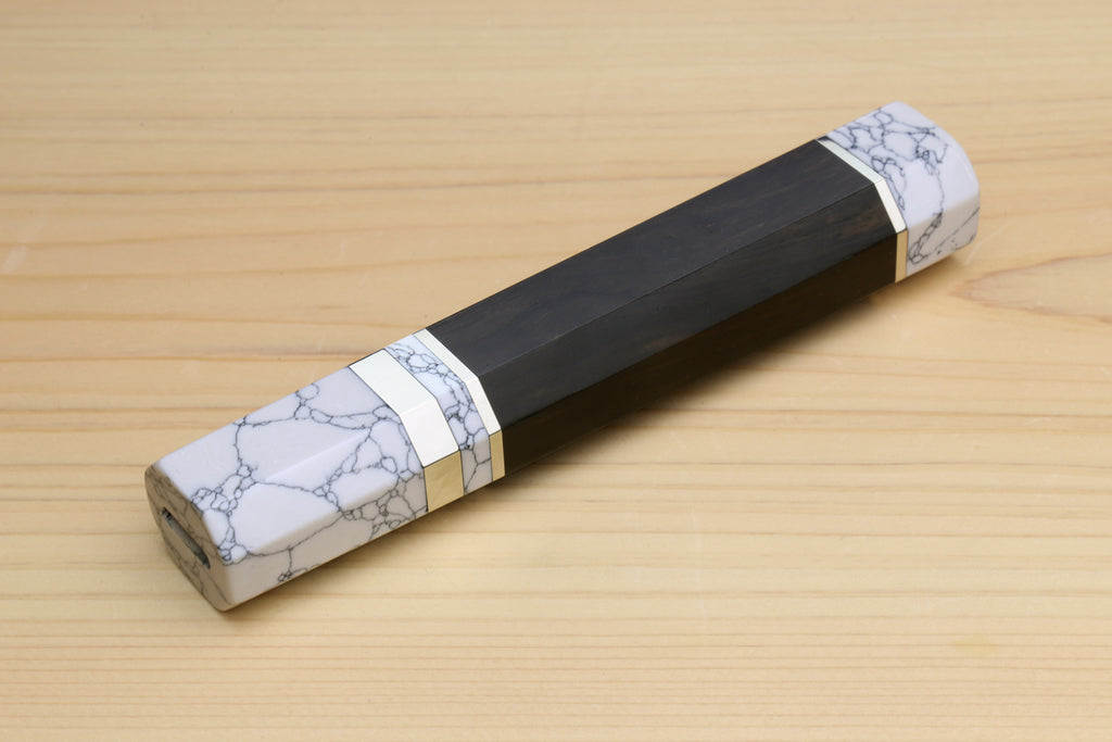 Ebony knife handle with white howlite bolster and gold-tone band, angled view