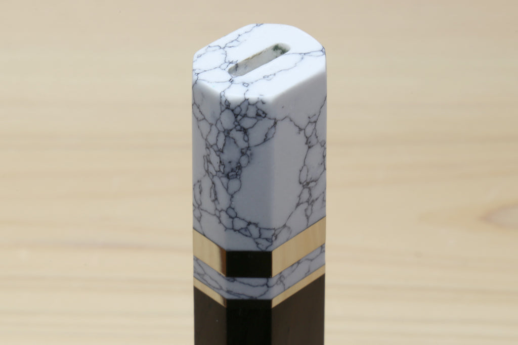 White howlite bolster end cap on an ebony knife handle with gold-tone band