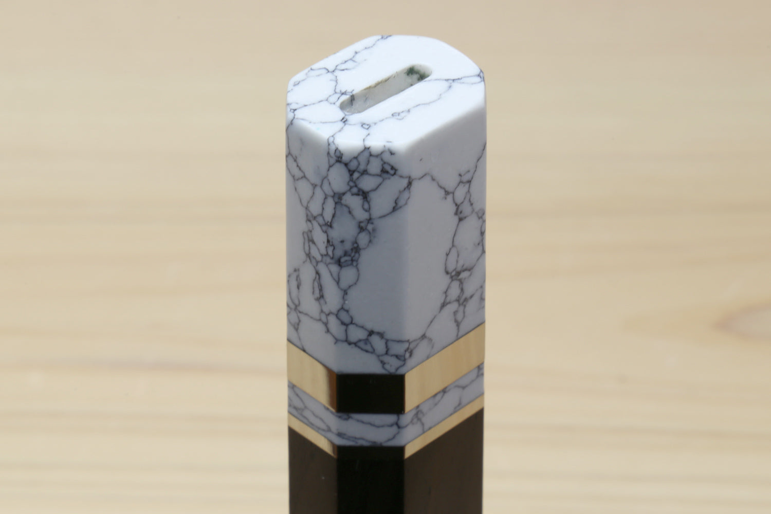 White howlite bolster end cap on an ebony knife handle with gold-tone band