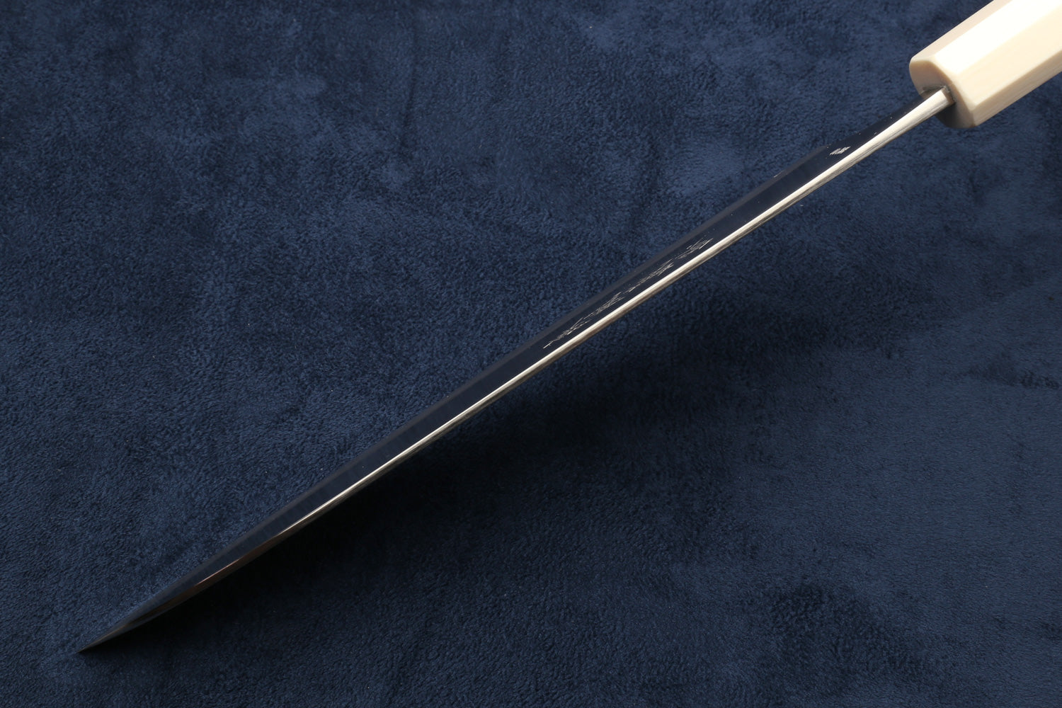 Chef's gyuto knife with pointed tip and ivory-pattern handle; side view.