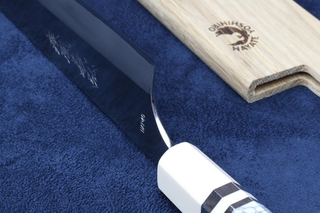 Chef's gyuto knife with dark sheath and ivory-pattern bolster; close-up view.