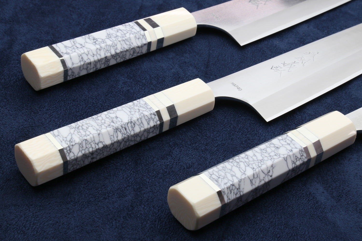 Pair of chef's gyuto knives with white blades and ivory-pattern handles.