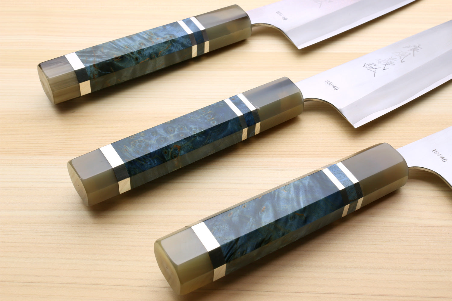 Set of Gyuto chef's knives with blue handles and matching wooden saya