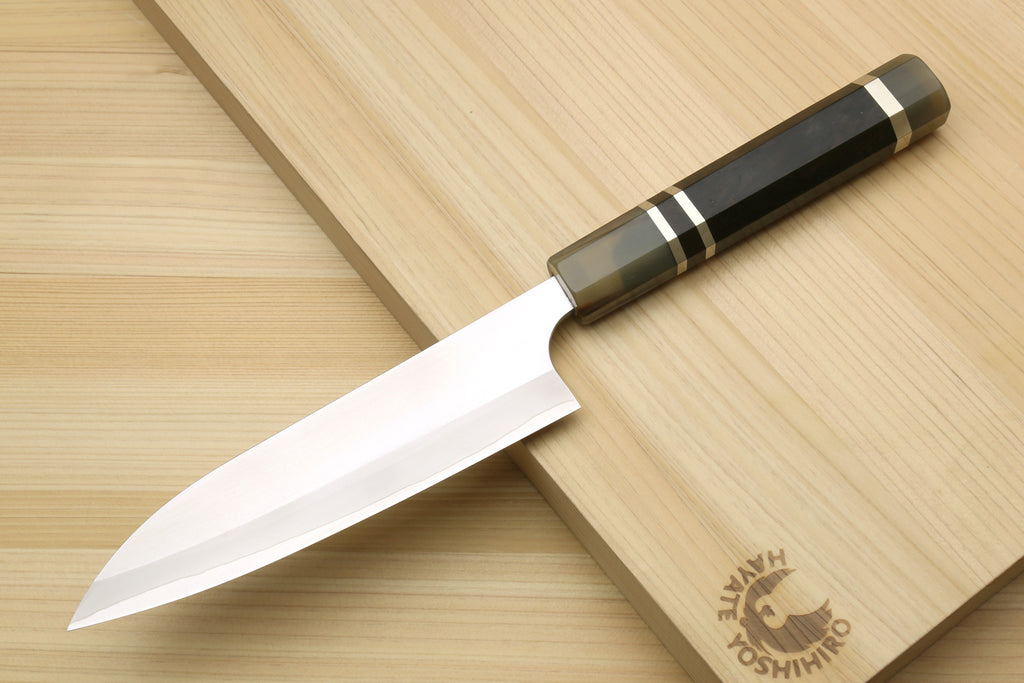 Petty chef knife with white blade and triple-ring handle on wooden board