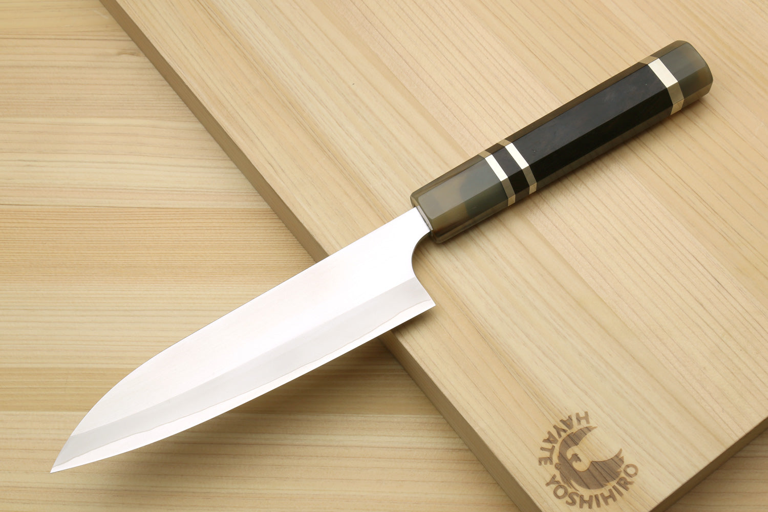 Petty chef knife with white blade and triple-ring handle on wooden board