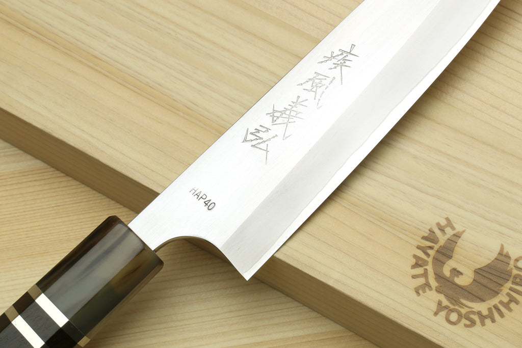 Petty chef knife blade close-up with etched marks and dark triple-ring handle