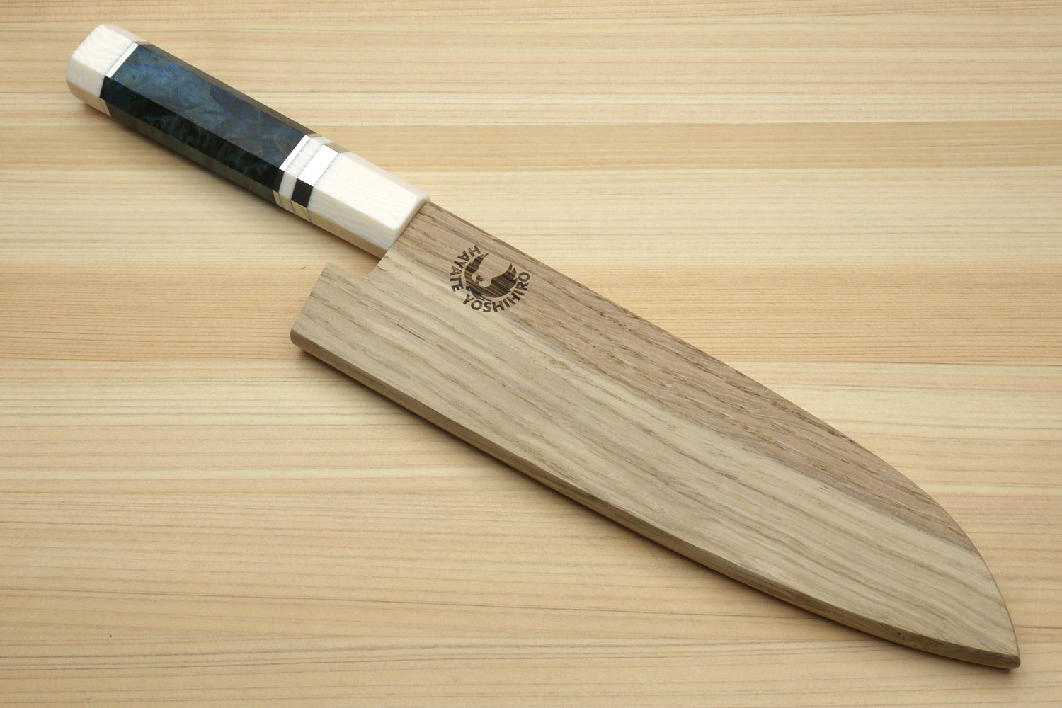 Santoku knife with dark blue handle next to wooden saya with logo