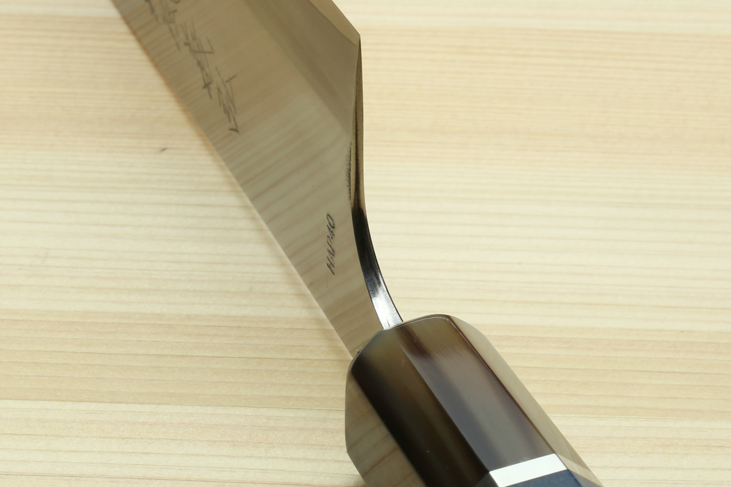 Santoku chef's knife tip close-up with stamped markings on white blade and dark handle