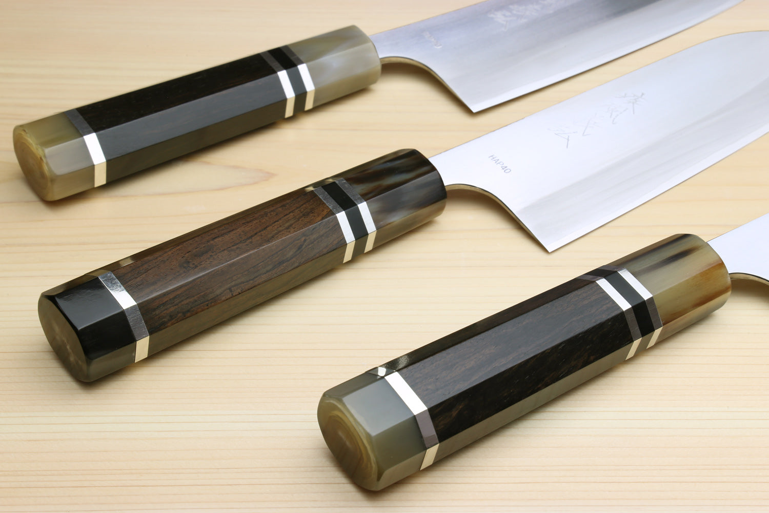 Three Santoku knives with ebony octagonal handles and triple-ring accents