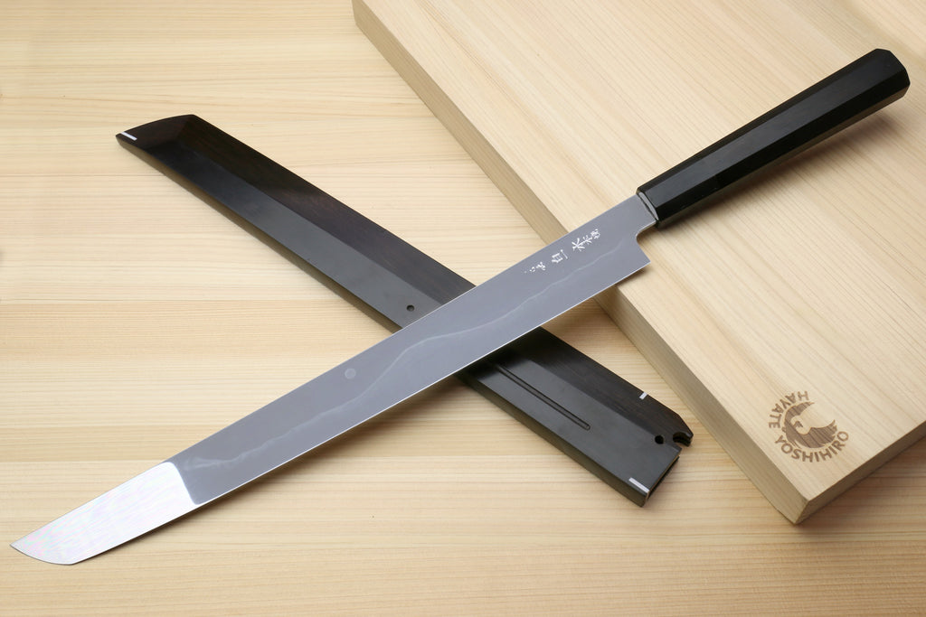 Japanese kitchen knife with silver blade, black handle, and dark sheath shown together