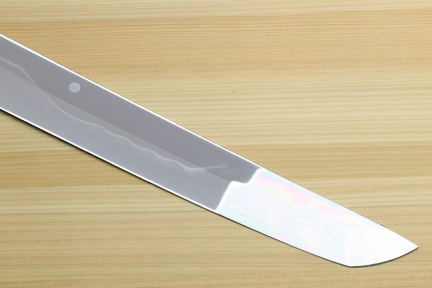 Japanese kitchen knife blade close-up with mirror-finished silver edge and pointed tip