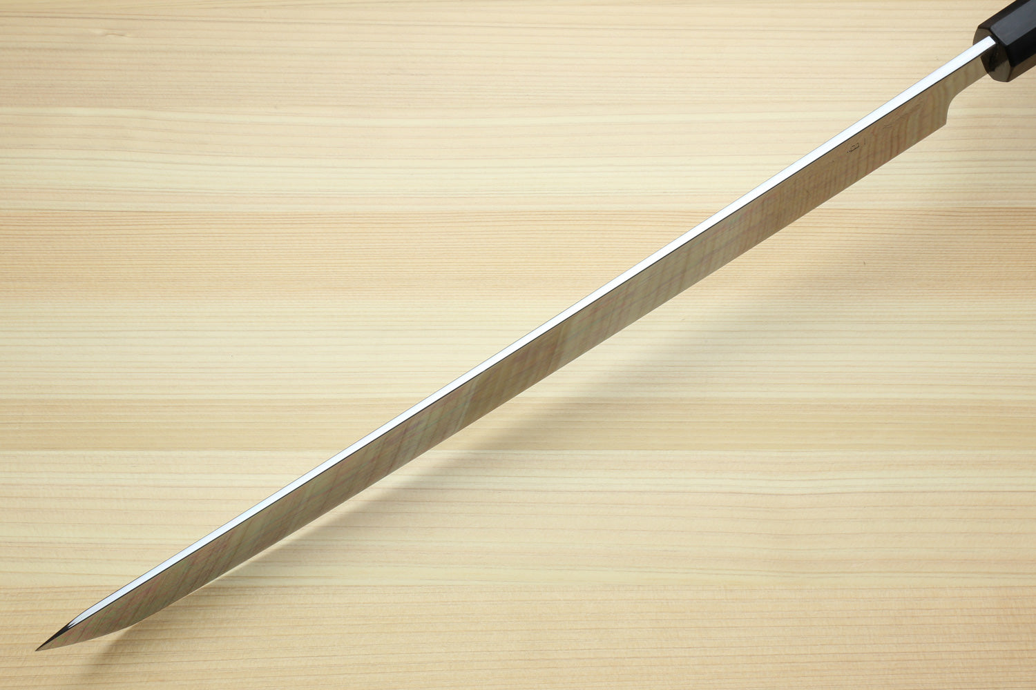 Japanese kitchen knife with long silver blade and dark handle, side view