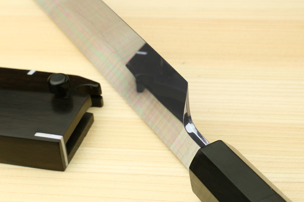 Japanese kitchen knife with mirror-finished blade and black handle, close-up