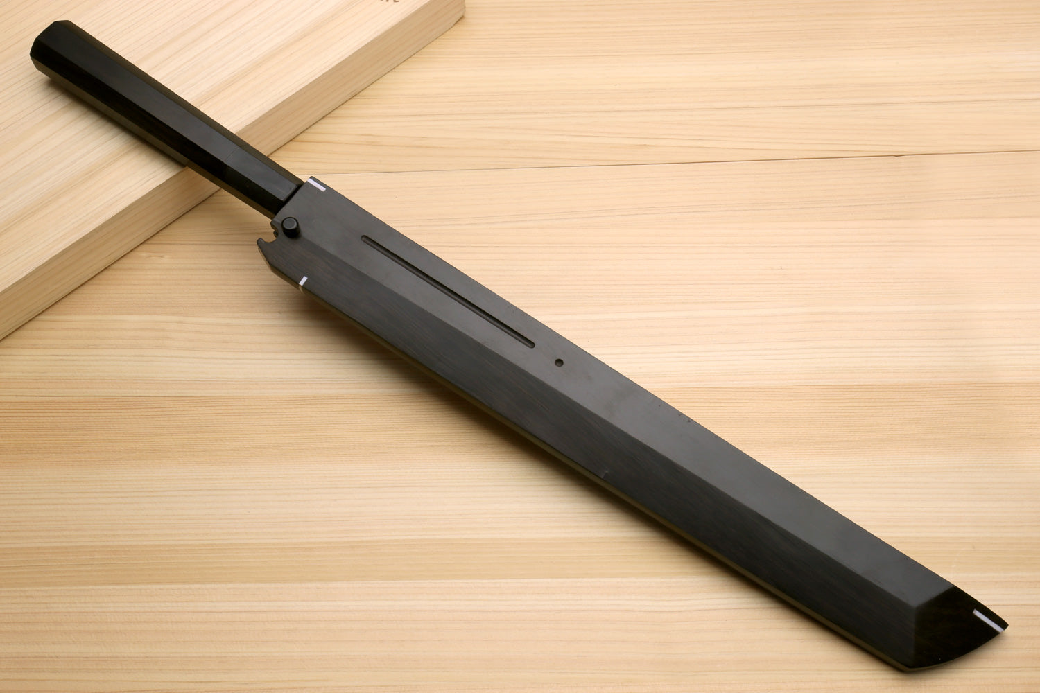 Japanese kitchen knife with dark sheath and silver blade, resting on wooden board