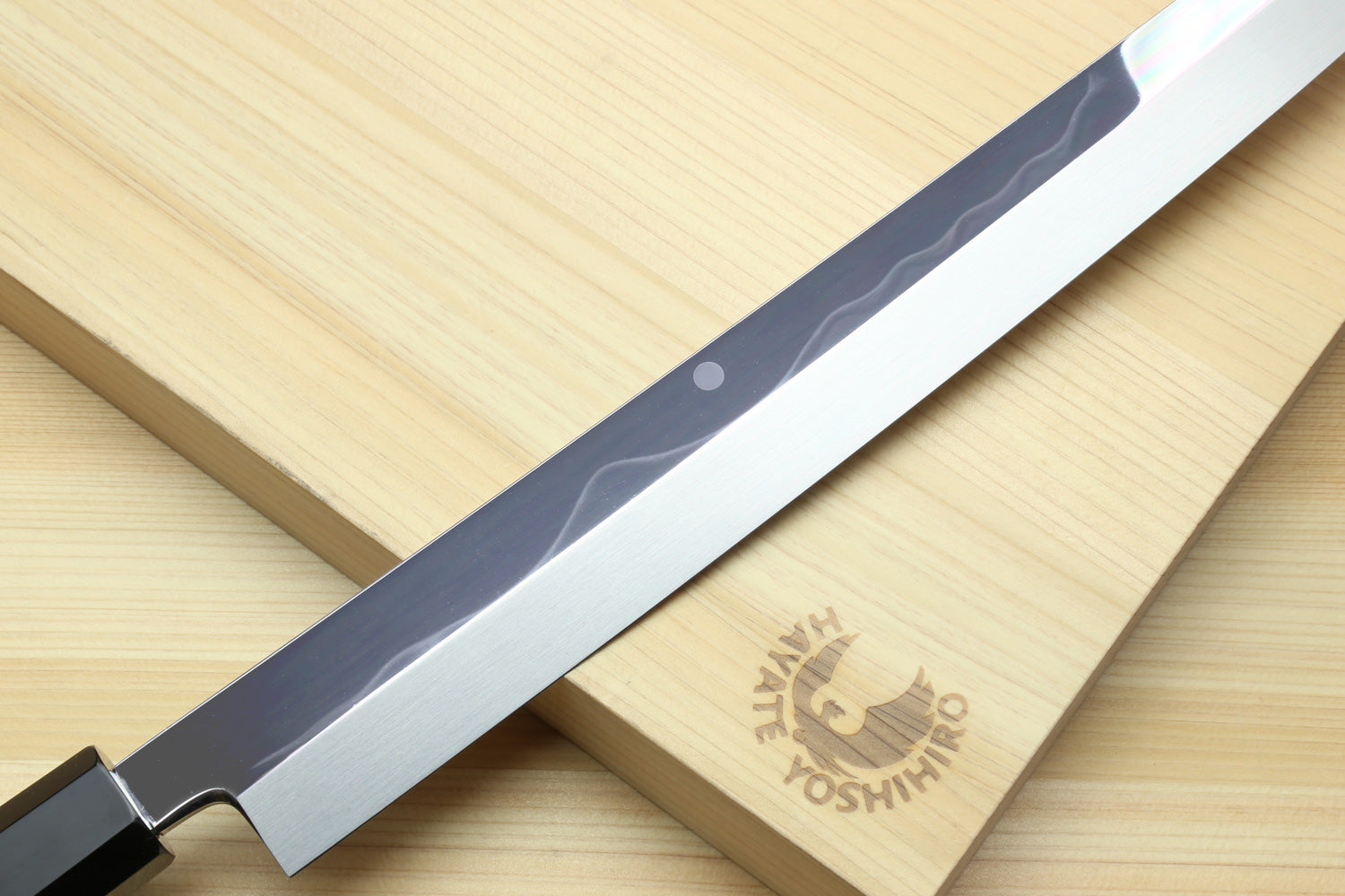 Japanese knife blade detail with dark handle and chrome-like mirror finish.