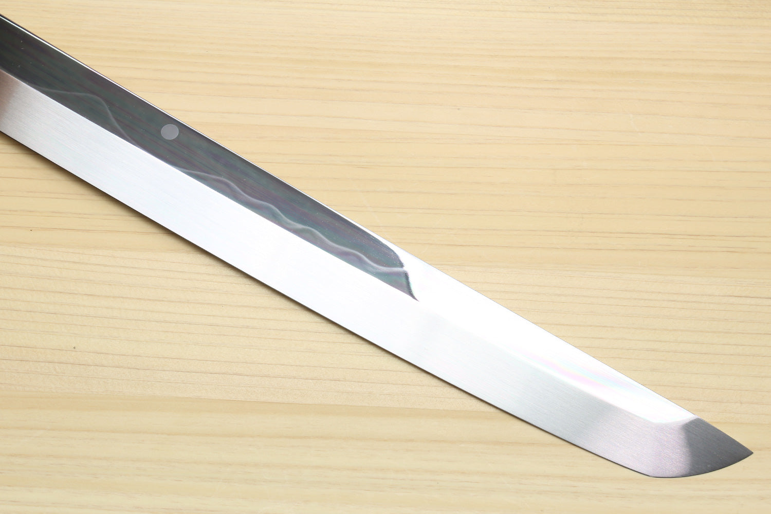 Mirror-finished steel Japanese knife blade with wavy pattern, pointed tip.