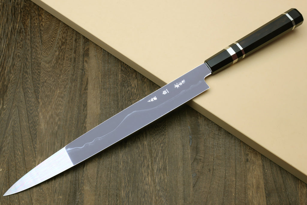 Japanese chef knife with silver blade and etched marks, black striped handle