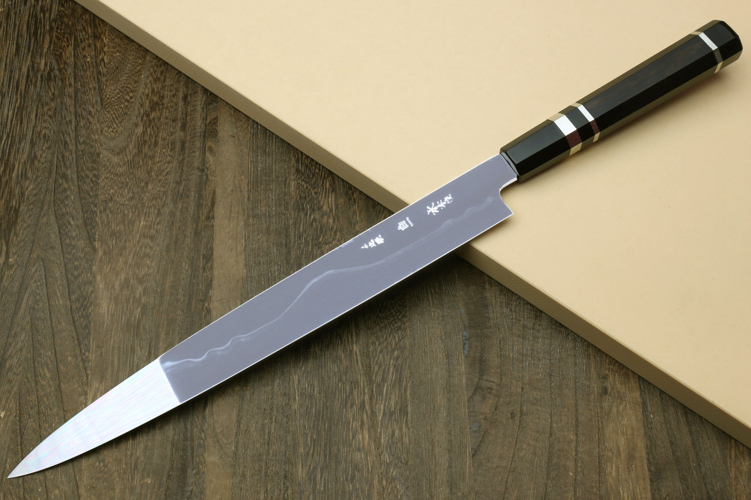 Japanese chef knife with silver blade and etched marks, black striped handle