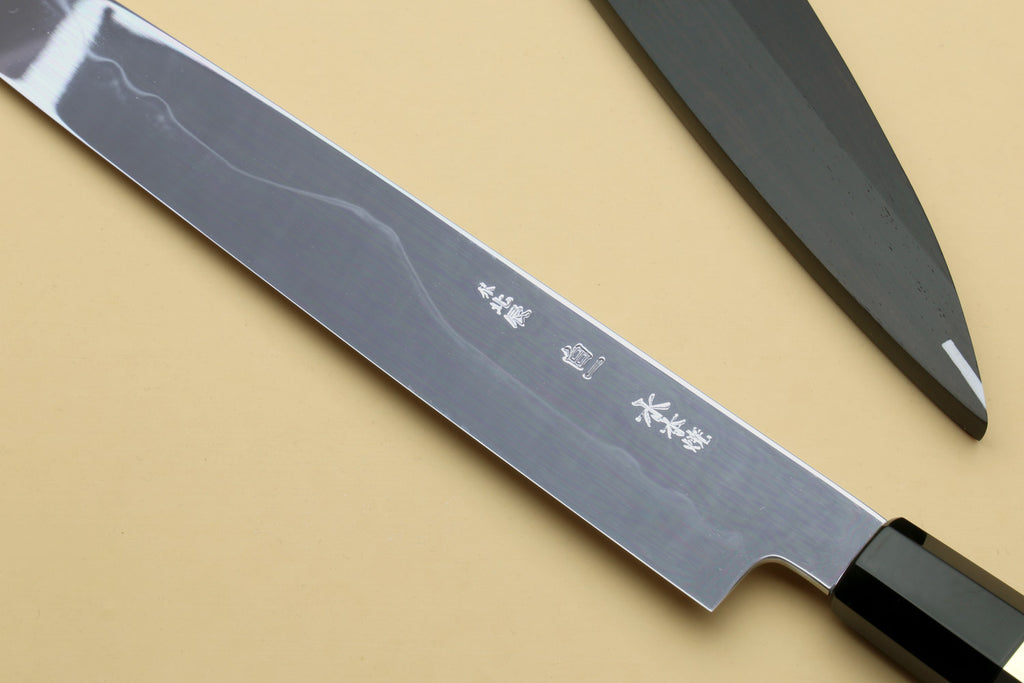 Japanese chef knife blade close-up with etched text and black striped handle