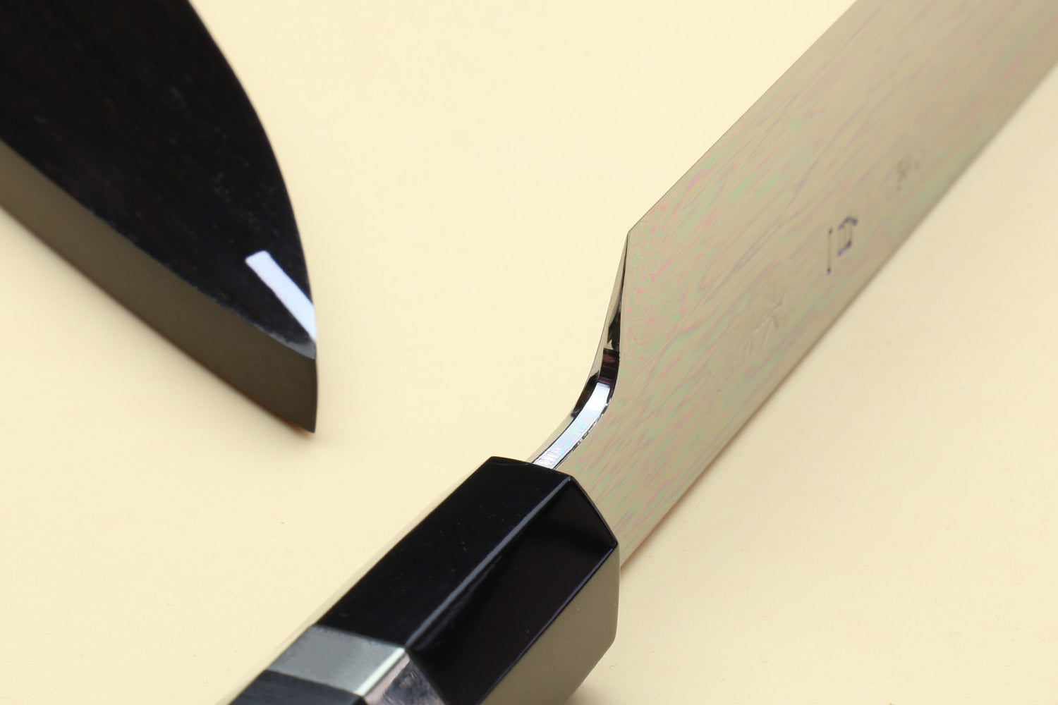 Japanese chef knife with silver blade and black handle, partially in saya