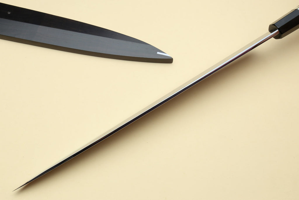 Japanese chef knives with pointed silver blades and black striped handles, angled view