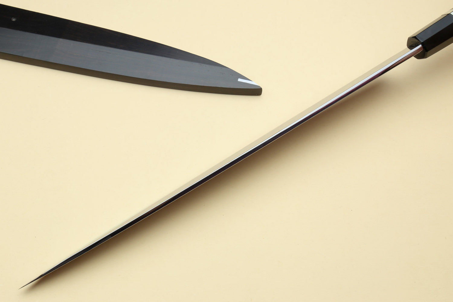 Japanese chef knives with pointed silver blades and black striped handles, angled view