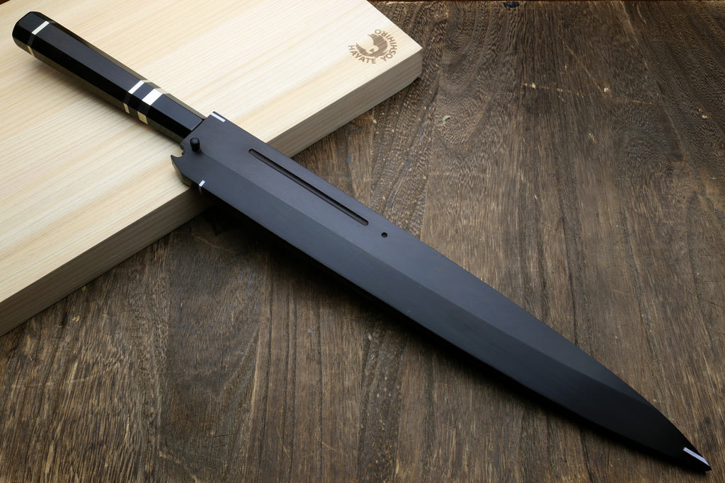 Japanese chef’s knife on wooden board with ebony handle and black scabbard.